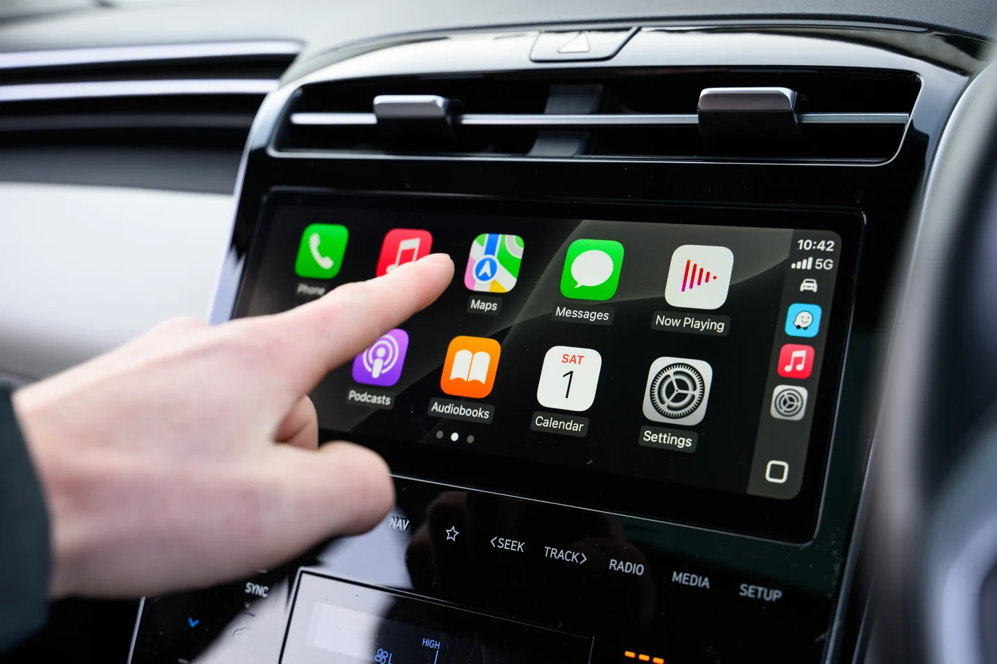 CarPlay em uma central integrada ao painel, com os aplicativos e botões físicos visíveis